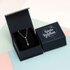 Silver necklace in an open black box with 'Happy Raksha Bandhan' text on a pastel background
